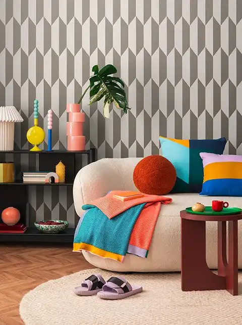 Wohnzimmer mit grafischer Tapete in Grau und Weiß, cremefarbenem Sofa und bunten Kissen, Beispiel für Tapeten für Wohnzimmer von MATEX